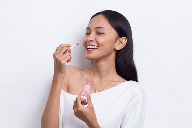 Hermosa joven asiática con lápiz labial aislado sobre fondo blanco.