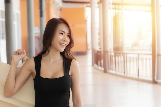Hermosa joven asiática lleva bolsas de compras con bolsas de compras disfrutando de compras y sonriendo mientras hace compras en el outlet, centro comercial.