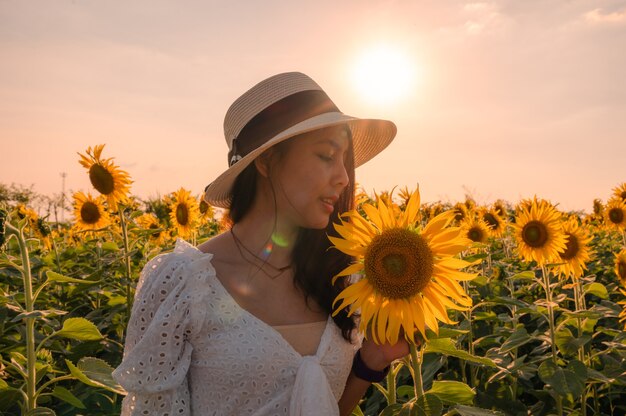 Hermosa joven asiática de pie en el jardín floreciente de girasol en la noche