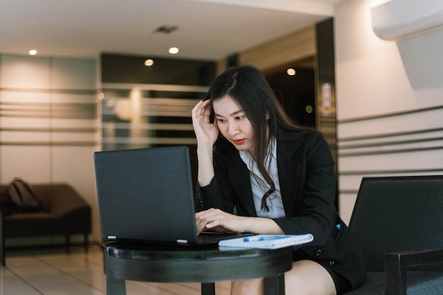 Foto hermosa joven asiática que usa su computadora portátil