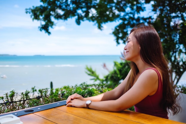 Una hermosa joven asiática sentada y mirando el mar y el cielo azul