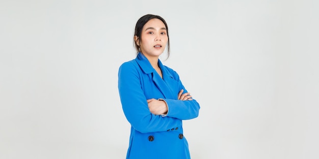 Hermosa joven asiática sonríe alegremente mientras está de pie con el brazo cruzado en el uniforme de la chaqueta azul. Atractiva mujer feliz y confiada para la moda haciéndose pasar por un profesional de la belleza para el cuidado de la salud.