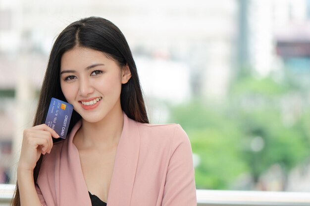 hermosa joven asiática sonriendo mientras usa tarjeta de crédito para comprar en línea