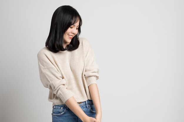 Hermosa joven asiática sonriente y feliz. Encantadora mujer de pie sobre fondo blanco aislado.