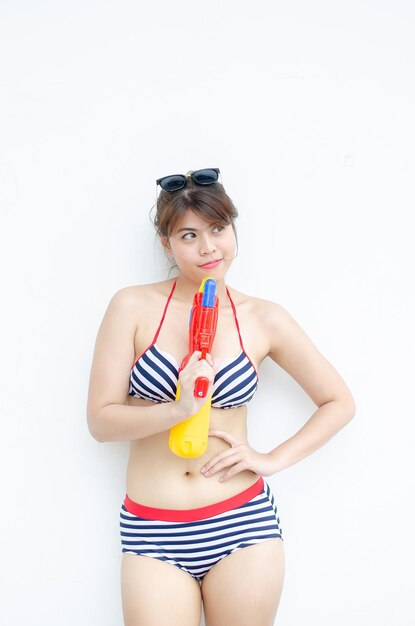 Hermosa joven asiática sosteniendo una pistola de agua y sonriendo en el día del festival Songkran en Tailandia