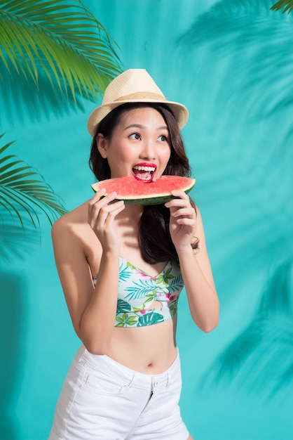 Hermosa joven asiática sosteniendo una rebanada de sandía y sonriendo