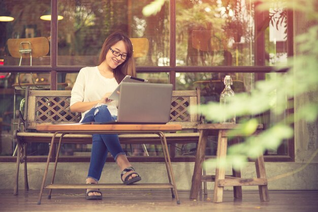 Hermosa joven asiática trabajando en una cafetería con una computadora portátil. mujer freelance