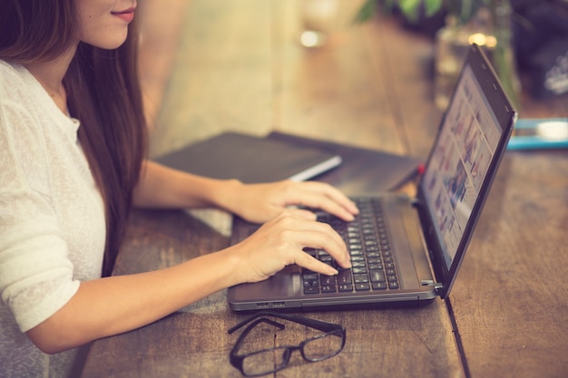 Hermosa joven asiática trabajando en una cafetería con una computadora portátil