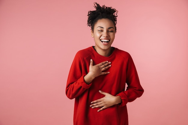 hermosa joven asombrosa feliz riendo emocionada mujer africana posando aislada sobre pared rosa.