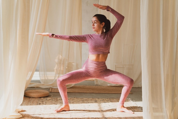 Hermosa joven atlética haciendo estiramientos de yoga en una acogedora habitación soleada