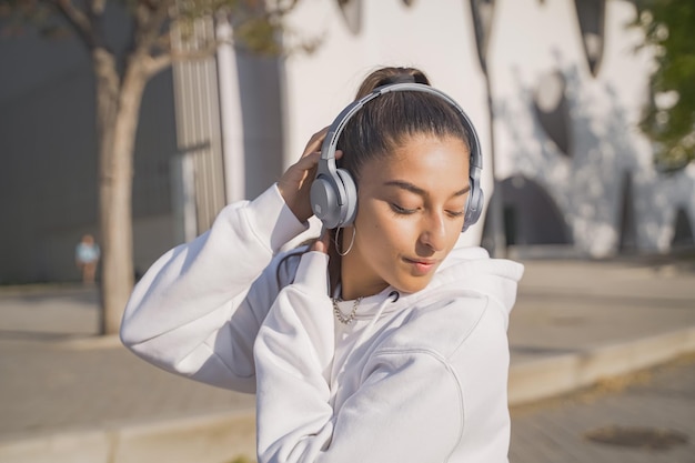 Hermosa joven con auriculares feliz sonriendo y bailando en la calle