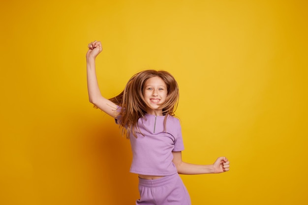 Una hermosa joven baila riéndose y divirtiéndose en un fondo amarillo limpio