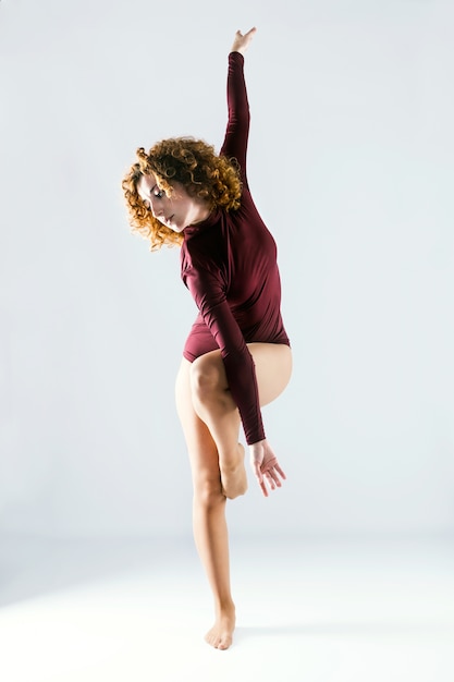 Foto hermosa joven bailarina profesional bailando sobre fondo blanco.
