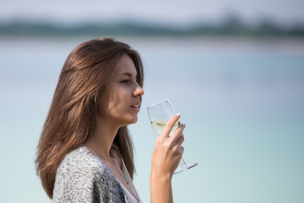 Hermosa joven bebe vino de un vaso.