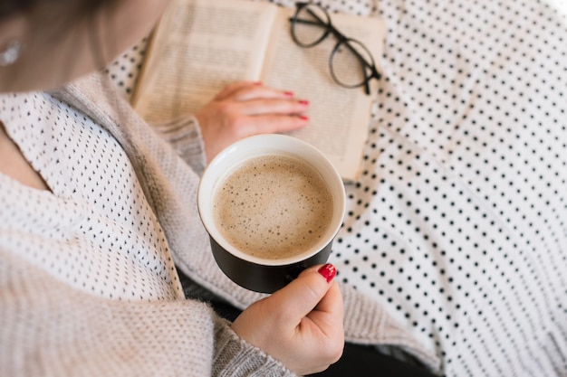 Hermosa joven bebiendo café capuchino, manicura laca gel rojo perfecto.