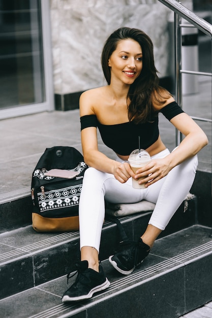 Hermosa joven bebiendo café en la ciudad