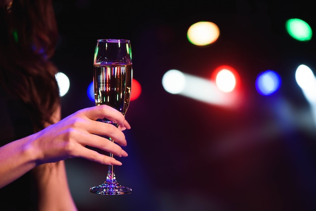 Hermosa joven bebiendo champán en la fiesta sobre luces