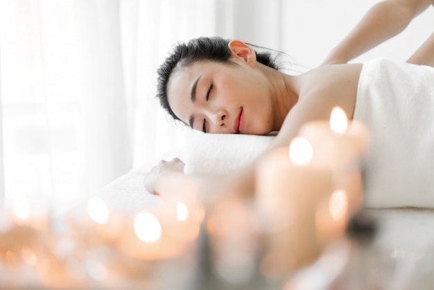 Hermosa joven belleza tratamiento de la piel relajante tumbado en una toalla en el salón de masajes y spa