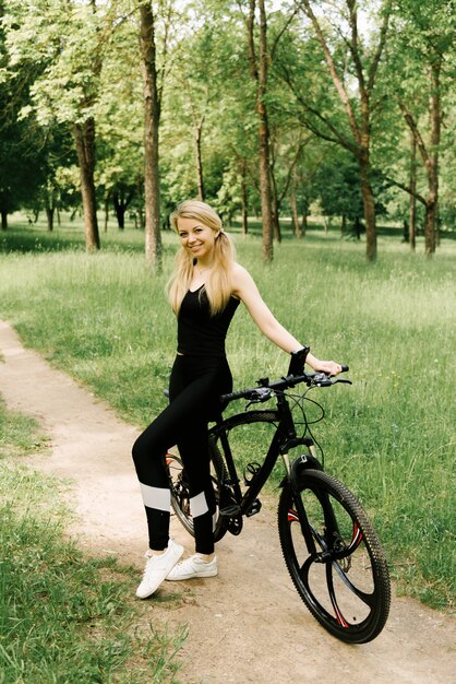 Hermosa joven con una bicicleta en el parque