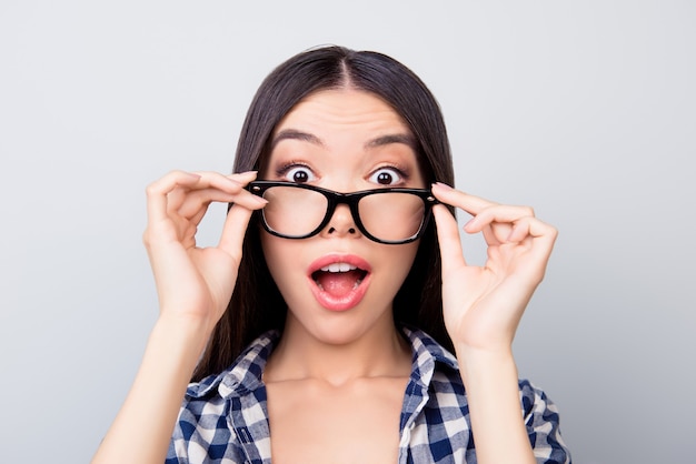 Hermosa joven con la boca abierta tocando sus gafas