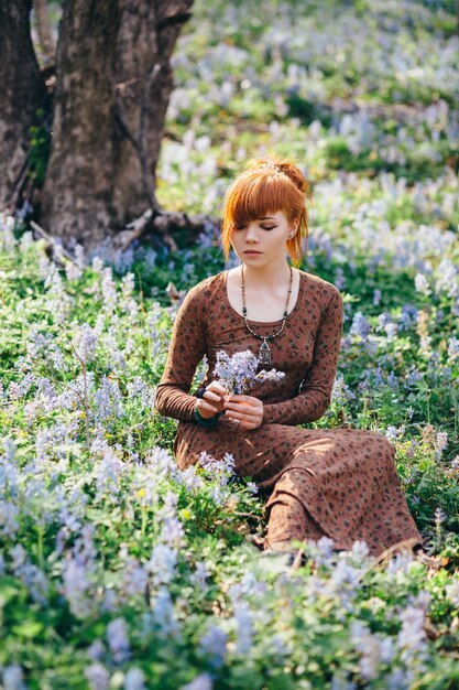 Hermosa joven en el bosque con flores de primavera