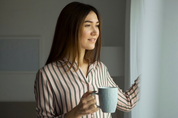 Hermosa joven de buen humor en pijama en el dormitorio