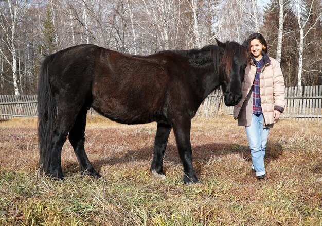 Hermosa joven con un caballo en el campo