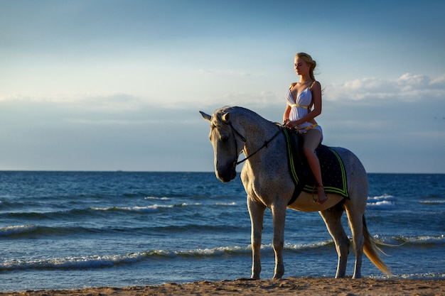 Hermosa joven en un caballo cerca del mar