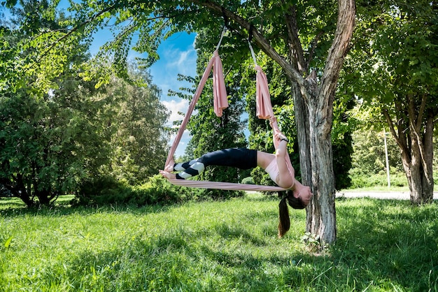 Hermosa joven con cabello hermoso en la naturaleza se extiende sobre una mosca de yoga al aire libre Concepto de mosca de yoga en la naturaleza