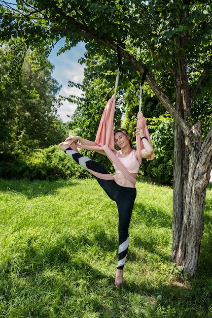 Hermosa joven con cabello hermoso en la naturaleza se extiende sobre una mosca de yoga al aire libre Concepto de mosca de yoga en la naturaleza