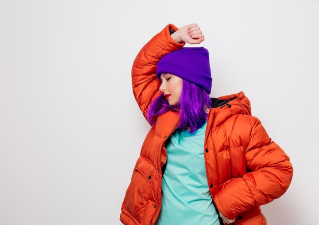 Hermosa joven con cabello morado y chaqueta naranja.