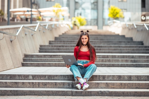 Hermosa joven en la calle usando una laptop