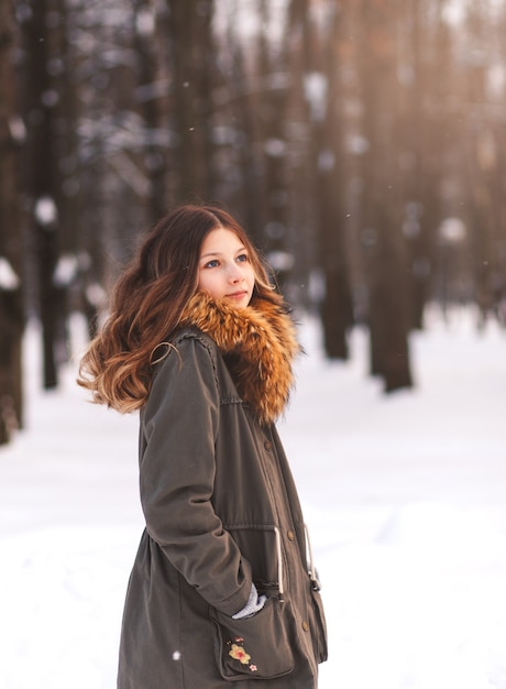 Hermosa joven camina en el parque en invierno en un día soleado