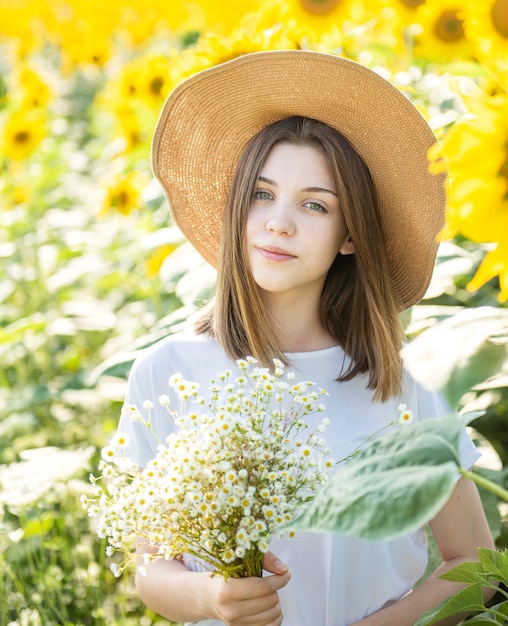 Hermosa joven camina en el verano en un campo con girasoles florecientes