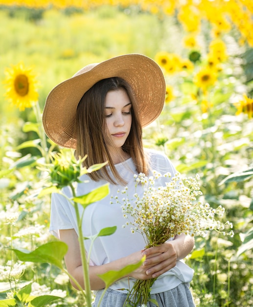 Hermosa joven camina en el verano en un campo con girasoles florecientes