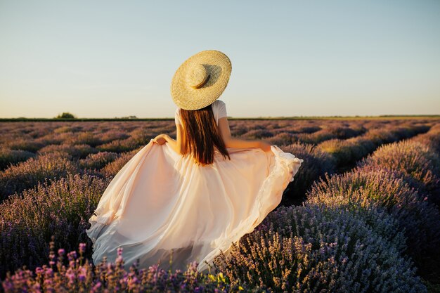 Hermosa joven caminando por el campo de lavanda en Provenza, Francia.