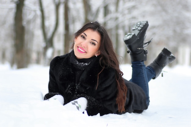 Hermosa joven caminando en el parque cubierto de nieve de invierno