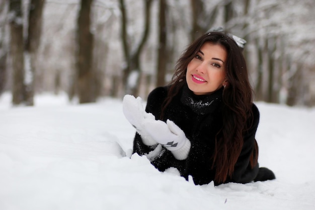 Hermosa joven caminando en el parque cubierto de nieve de invierno