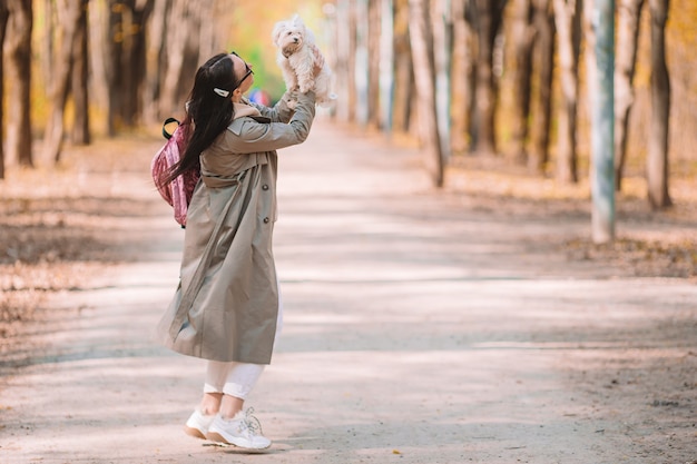 Hermosa joven caminando con perrito blanco