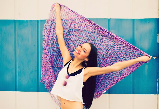 Una hermosa joven con una camiseta blanca y jeans azul tiene un gran pañuelo multicolor