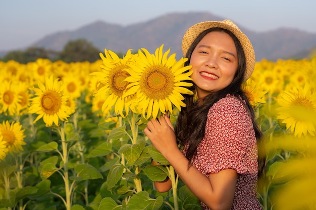 Hermosa joven en el campo de girasol con cielo azul