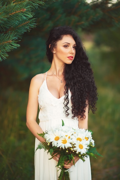 Hermosa joven en un campo con un vestido blanco