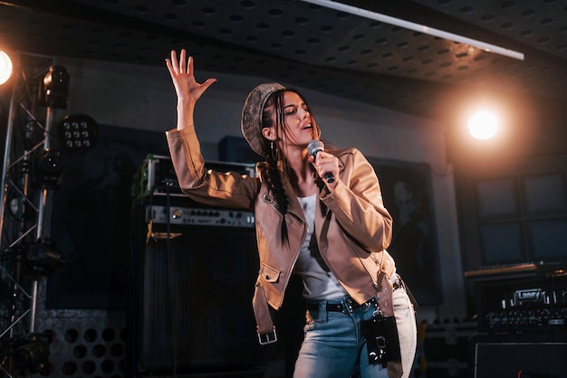 Hermosa joven cantante femenina ensayando en un estudio de grabación