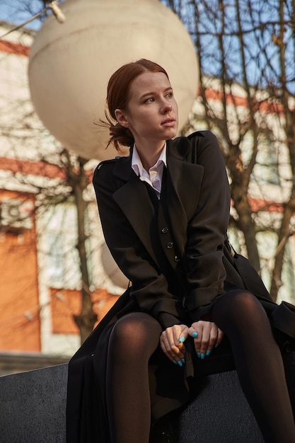 Hermosa joven caucásica con abrigo de pelo largo sentada al aire libre en el parque