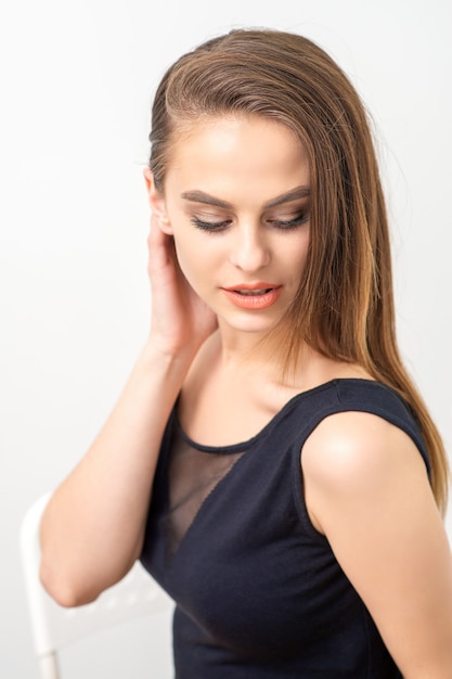 Hermosa joven caucásica con maquillaje natural sonriendo y mirando hacia abajo