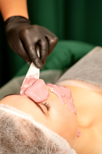 Hermosa joven caucásica recibiendo una máscara algínica en la cara en un salón de belleza Tratamiento facial de la piel