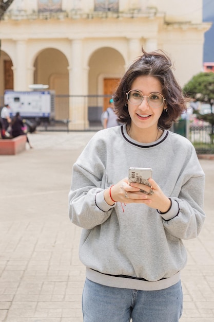 Hermosa joven caucásica sosteniendo el teléfono en las manos y sonriendo.