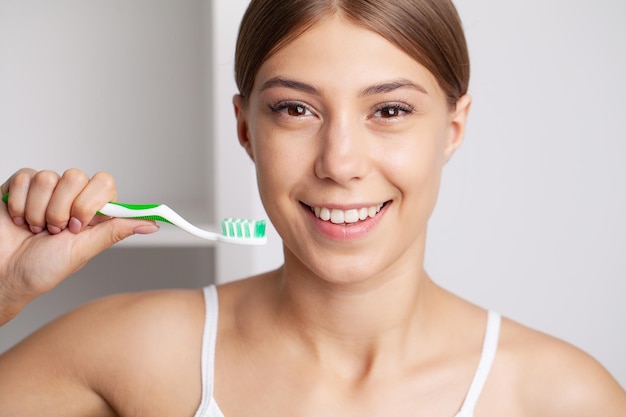 Hermosa joven se cepilla los dientes en el baño