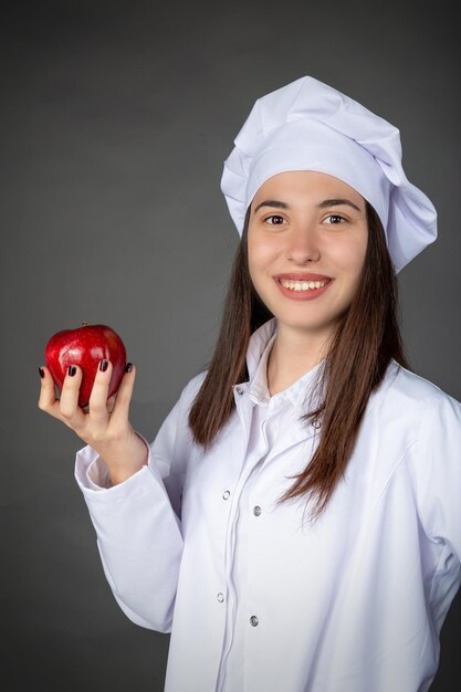 Hermosa joven chef turca manteniendo una manzana en su mano