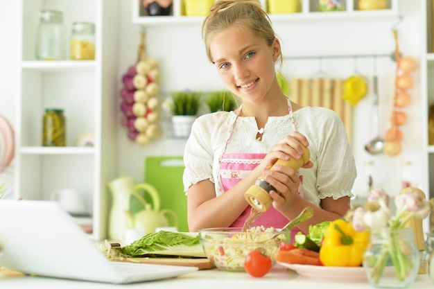 Hermosa joven en cocina con laptop